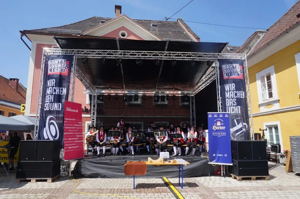 Blaskapelle auf Open-Air-Bühne mit Danyssoundlight-Bannern, sonniges Stadtfest.