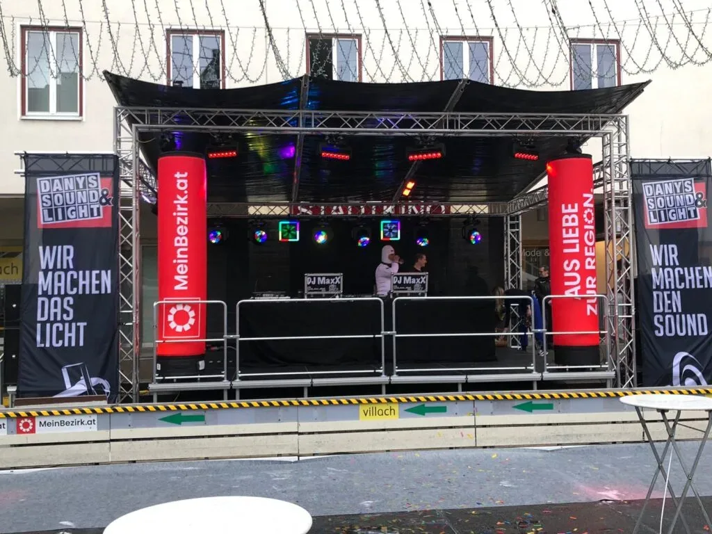 DJ-Bühne mit Lichteffekten und Bannern von Dany's Sound & Light bei einer Veranstaltung.